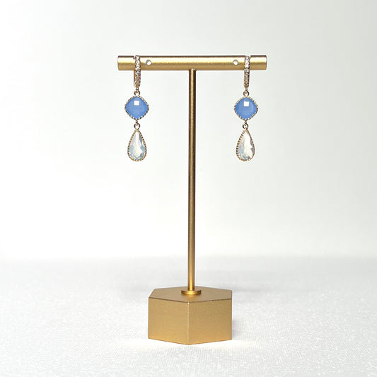 This earring set features a blue glass fancy prong set bezel charm with a milky white glass teardrop shaped prong set bezel hung by a gold filled CZ crested huggie style hoop.&nbsp;