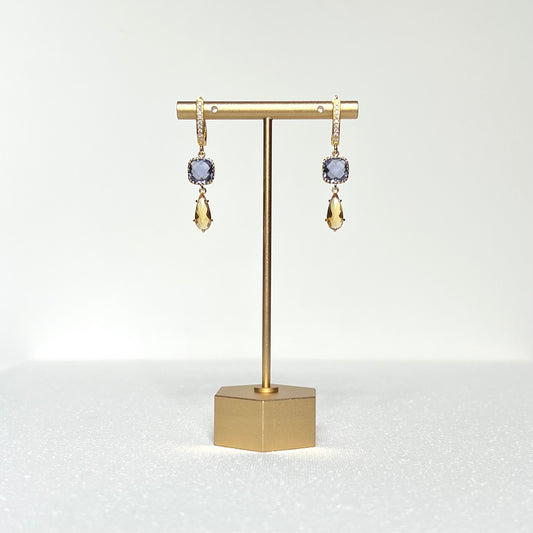 This pair of earrings features a tanzanite colored glass charm in a fancy prong bezel with a citrine colored glass teardrop shaped prong set charm hung by a CZ crested gold filled post style lever back earring.&nbsp;